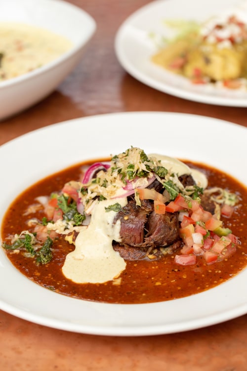 Braised all natural pork cheeks served with cascabel chile sauce, grandma’s corn cake and buttermilk cumin drizzle from Elote Cafe in Sedona, Arizona