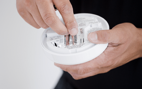 person inserting the batteries in the Smoke Detector
