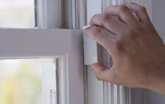 A hand placing the contact on the window frame