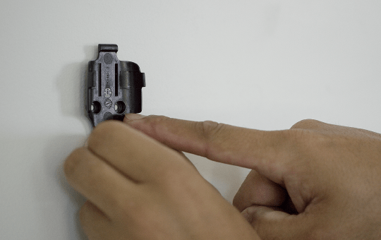 Hands pressing a wall mount of panic button to a wall