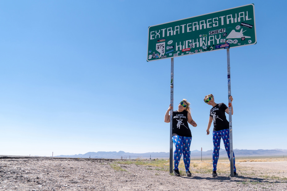 Two road-trippers pose under the Extraterrestrial Highway sign in Nevada.