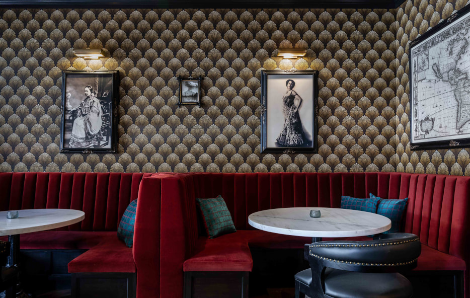 Red booths surrounded by historic images and wallpaper in the bar at National Exchange Hotel in Nevada City, California.