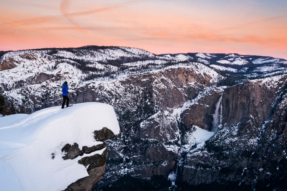A snowshoer perched on the Diving Board at Glacier Point in Yosemite National Park.