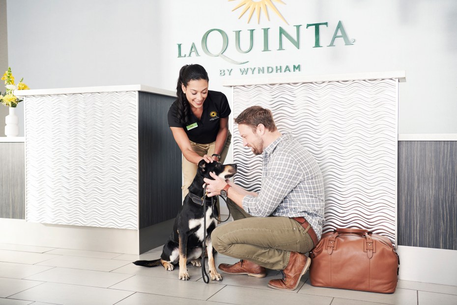 A man checks in with his dog at a La Quinta by Wyndham hotel.