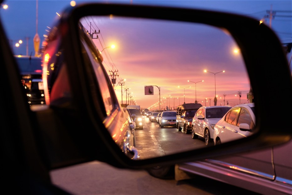 A car's side mirror with traffic and headlights reflected in it.