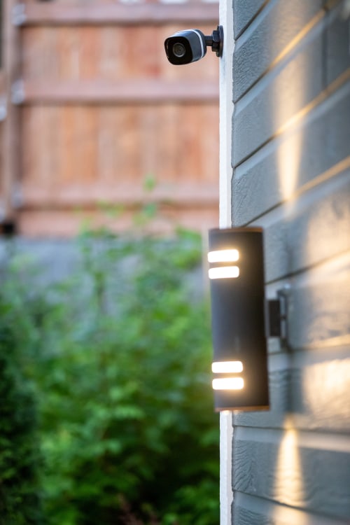 A security camera installed outside above a modern light.