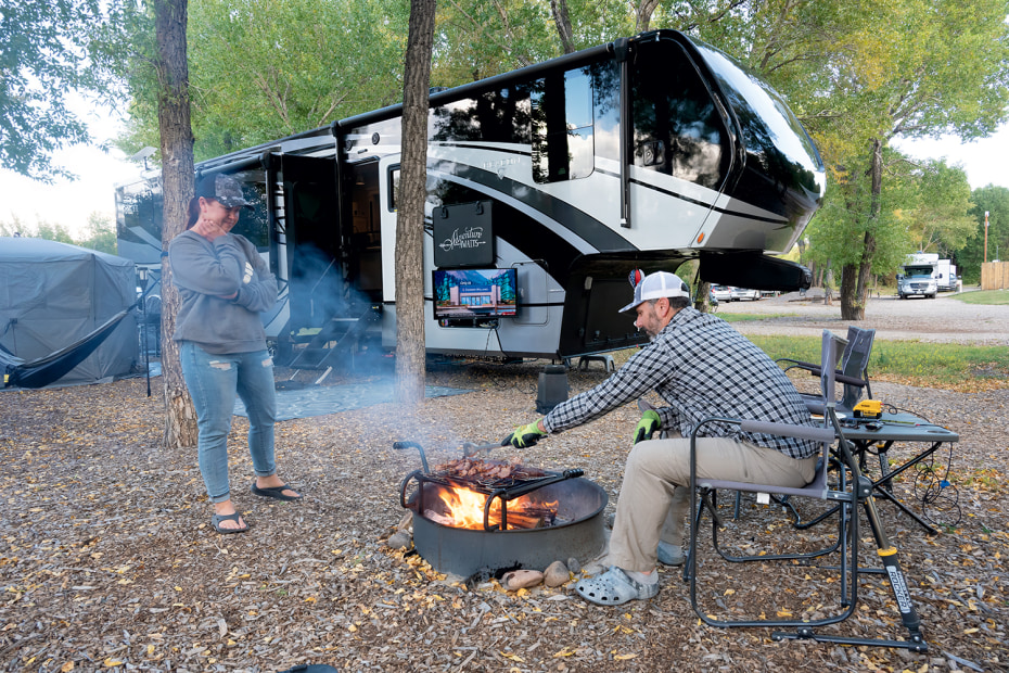 A couple cook over the firepit at their campsite in the Longhorn Ranch Lodge & RV Resort in Dubois, Wyoming.