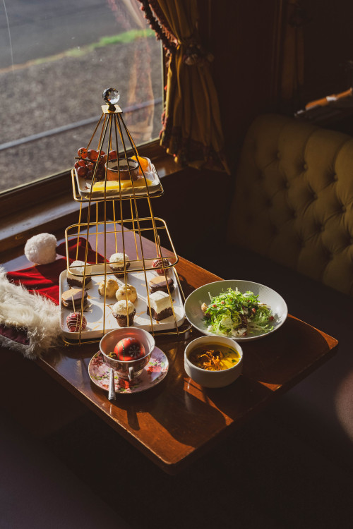 Three tiered tray and other foods on a table aboard the Napa Valley Wine Train as part of the tea service.