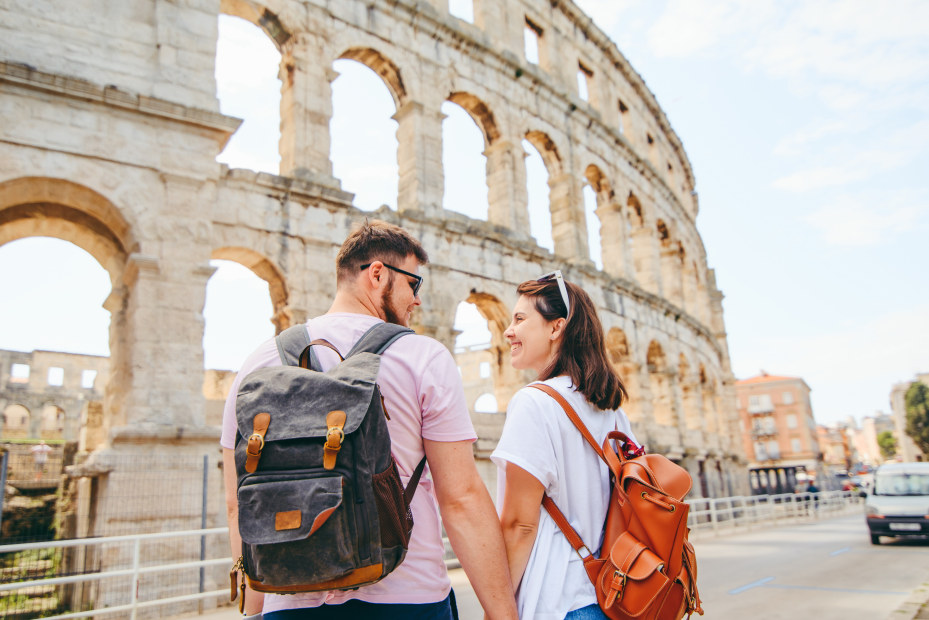 A couple hold hands in front of a coliseum in Pula, Croatia.