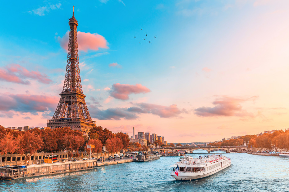 A river cruise goes down the Seine River with the Eiffel Tower in the background.