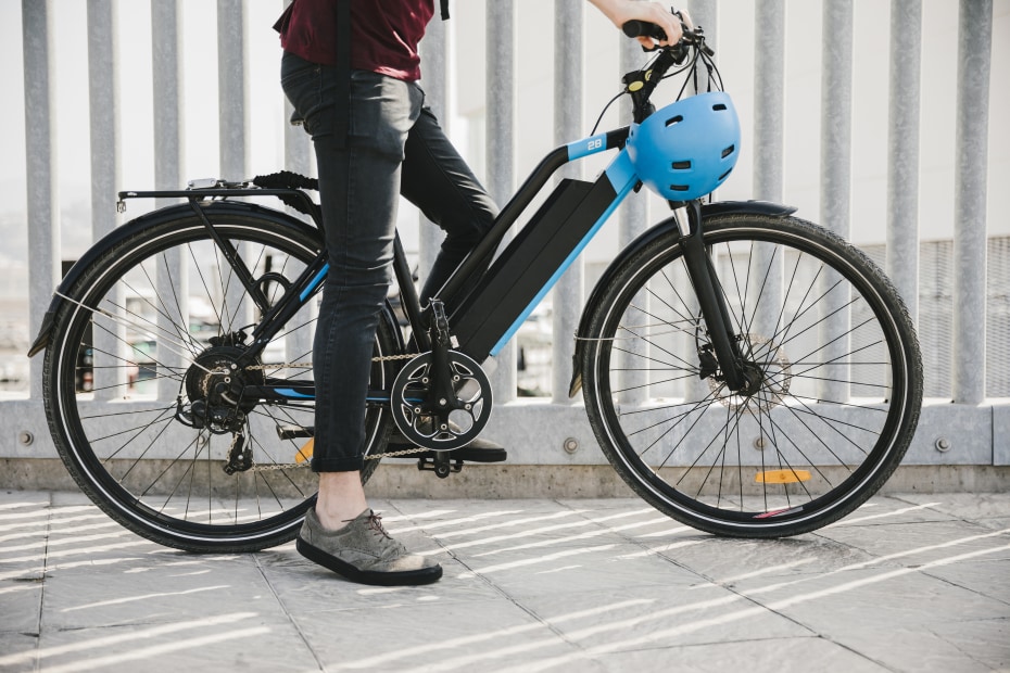 A person straddles an e-bike before putting on their helmet.