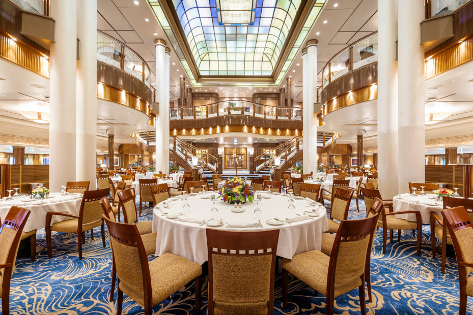 White tablecloths cover the round tables inside Cunard's Britannia Restaurant on Queen Mary 2..