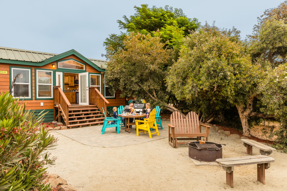 A family sits at an outdoor table outside one of the camping cabins at Santa Cruz/Monterey Bay KOA Holiday in Watsonville, California.