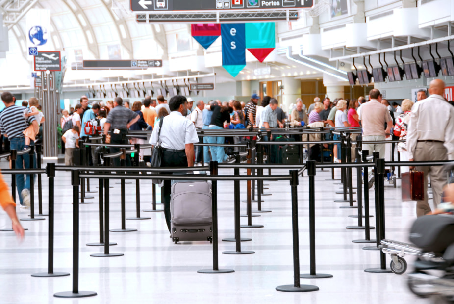 Travelers line up at airline counters to check their luggage.