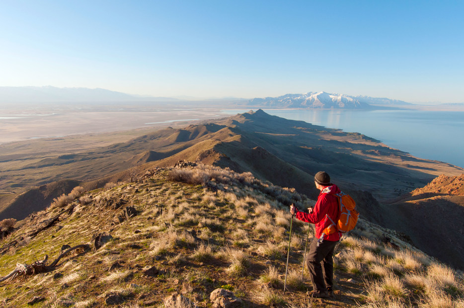 A male hiker stands on top of Frary Peak on Antelope Island, overlooking the Great Salt Lake.