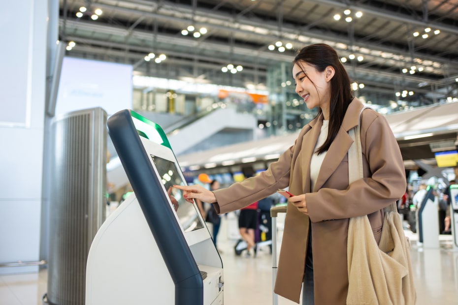 A woman uses a self check-in kiosk to check in for her international flight.
