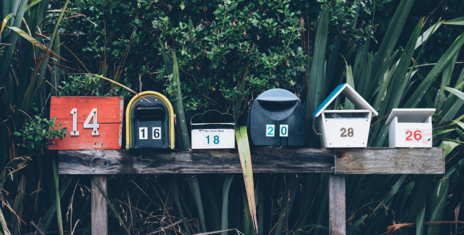 A row of mailboxes are lined up on a wooden post