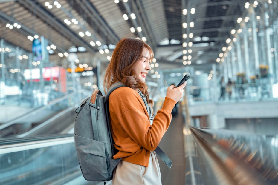 A woman uses the mobile passport control app on her phone as she walks through the airport.