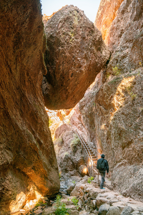 A hiker climbs the stairs under a large boulder to Bear Gulch reservoir.