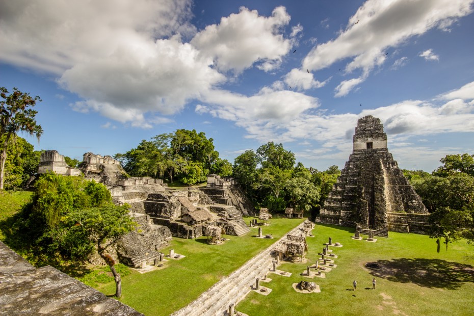 People tour a Mayan pyramid and ruins in Tikal National Park, Tikal, Guatemala.