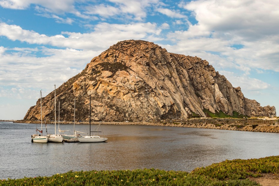 Boats float in the water in front of Morro Rock at Morro Bay State Park in California.