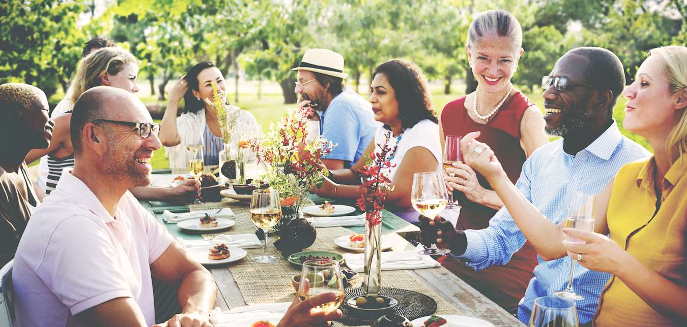 Family eating and chatting around a large outdoor table