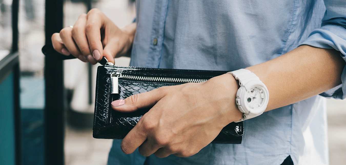 a woman's hands unzip her black wallet as she goes to remove her ID