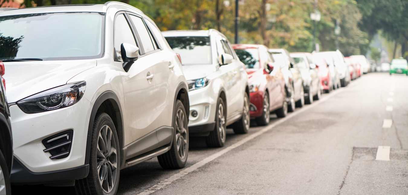 long line of cars parallel parked on a suburban street.