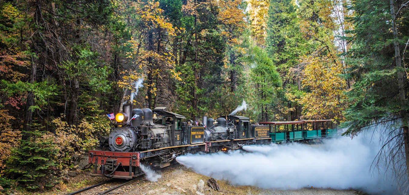 A small, historic steam train on the rails at Yosemite Mountain Sugar Pine Railroad in California.
