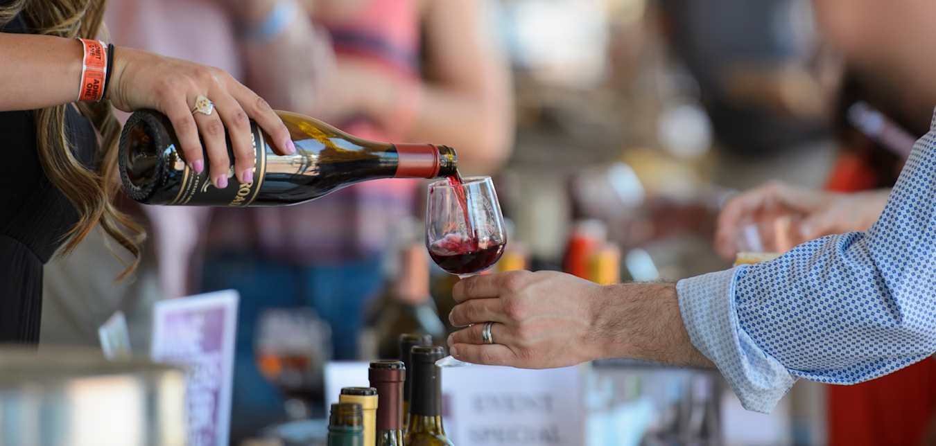 A vendor pours a glass of wine for a visitor at the Monterey Wine Festival in California.