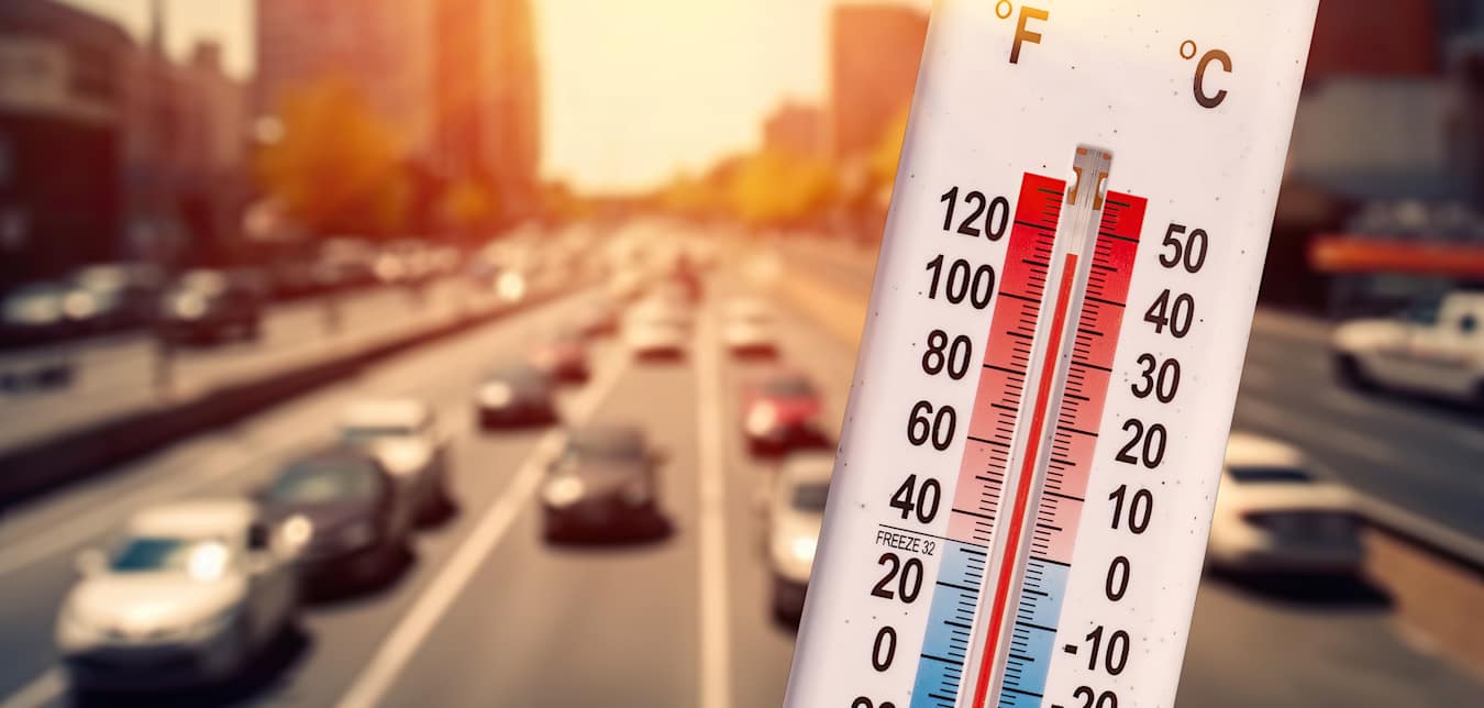 a thermometer shows a hot temperature in front of a freeway with cars on it