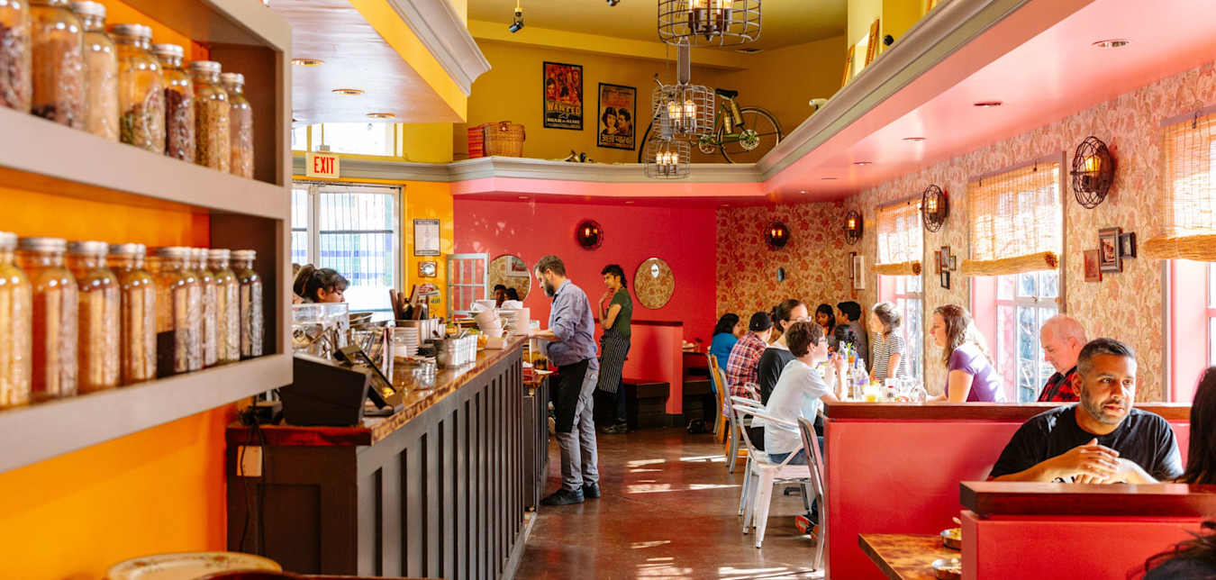 Spices and ethnic prints line the walls of a lively, colorful restaurant.