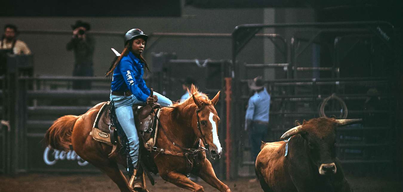 A female cattle roper on a horse on the Black rodeo circuit. 