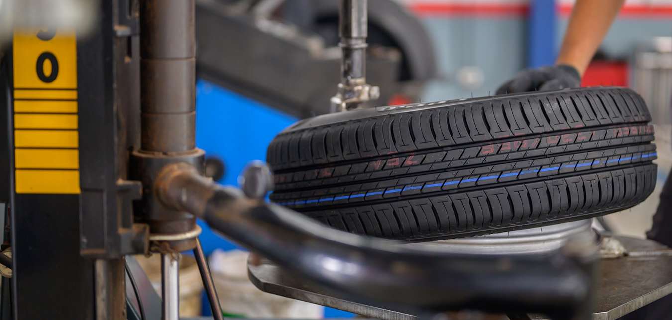 A mechanic mounts a tire on a rotation machine in a garage.