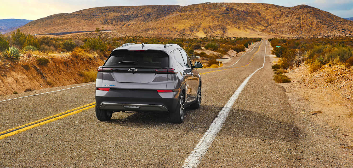 An electric Chevy Bolt SUV drives on a desert highway. 
