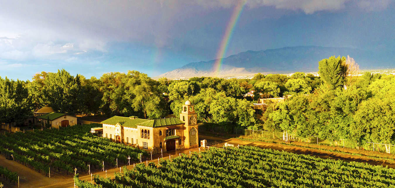 a rainbow over a vineyard and winery building