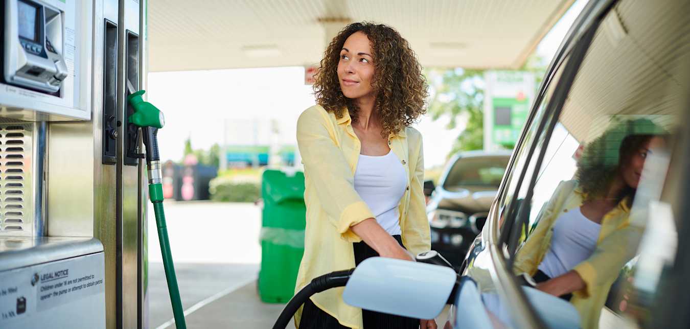 A woman fills her car at a gas station.