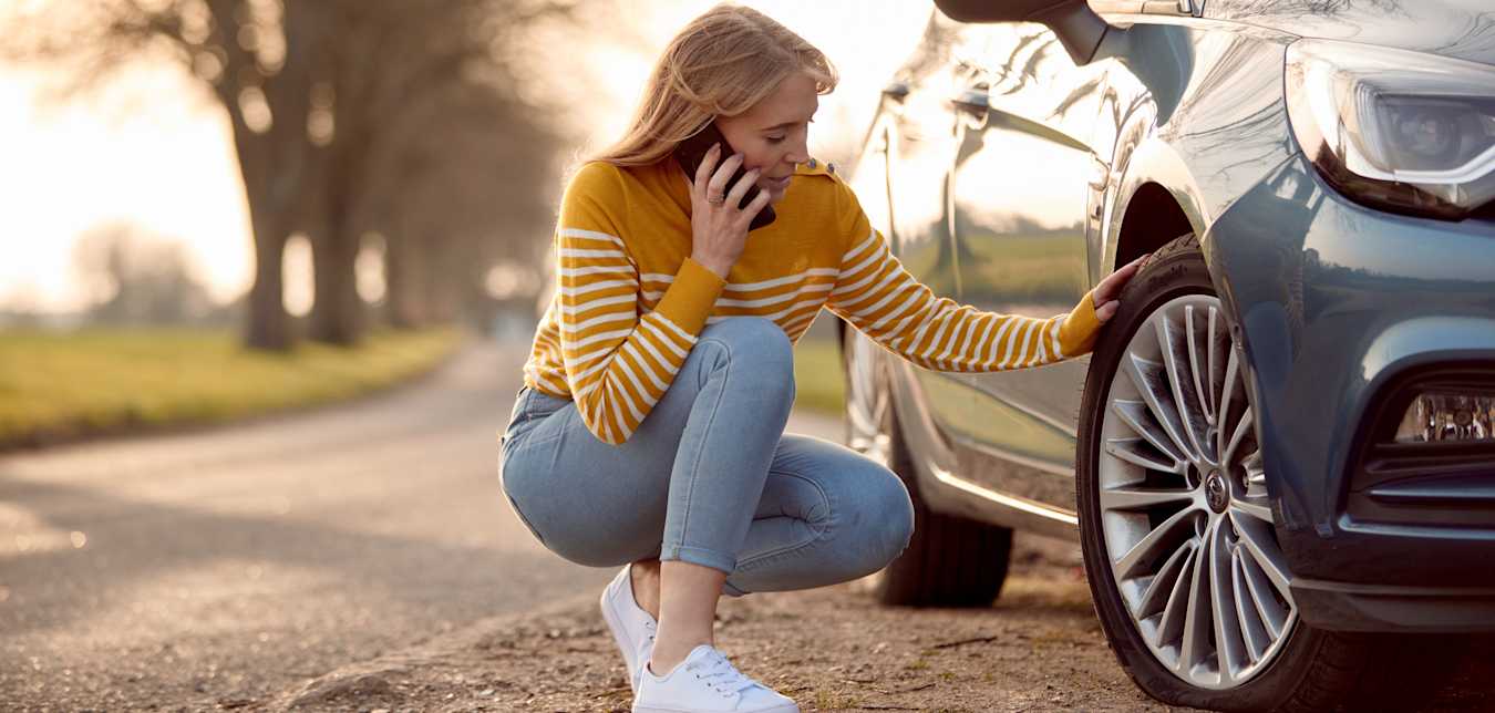 A woman with a flat tire calls for help.