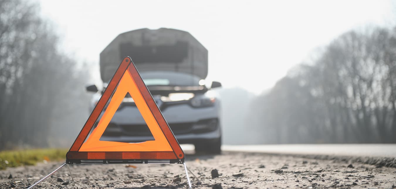 A car pulled over on the side of the road with a reflective warning triangle.