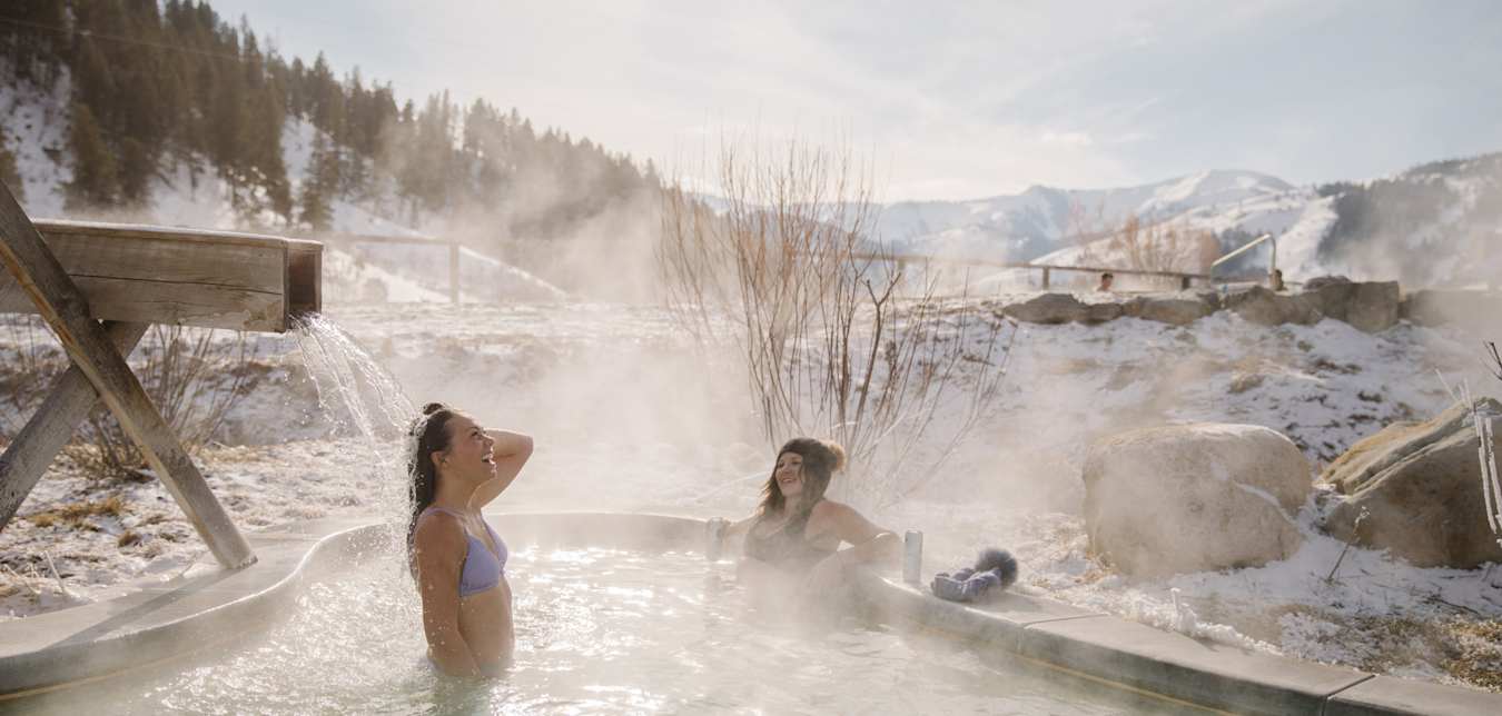 Friends soak at Astoria Hot Springs Park in Wyoming on a winter day.
