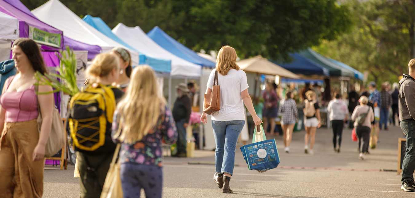 Shoppers walk between booths at the Clark Fork River Market in Missoula, Montana.