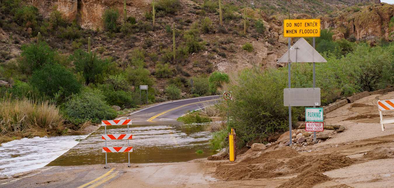 a flooded road in a mountain area with warning signs posted