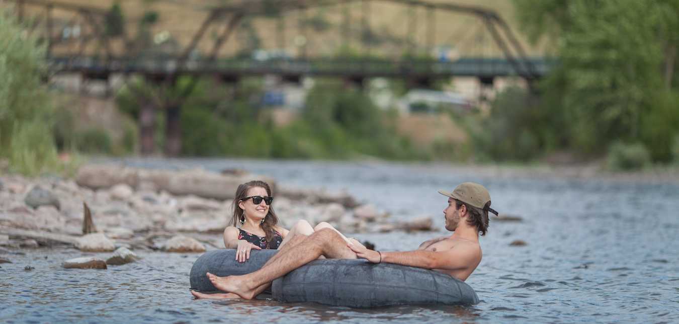 a woman and a man float in inner tubes on the Clark River in Missoula, Montana
