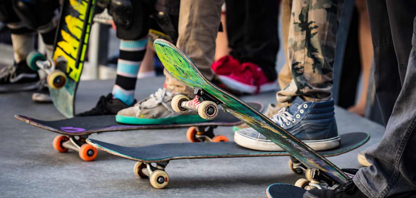 People stand on their skateboards at a skatepark.