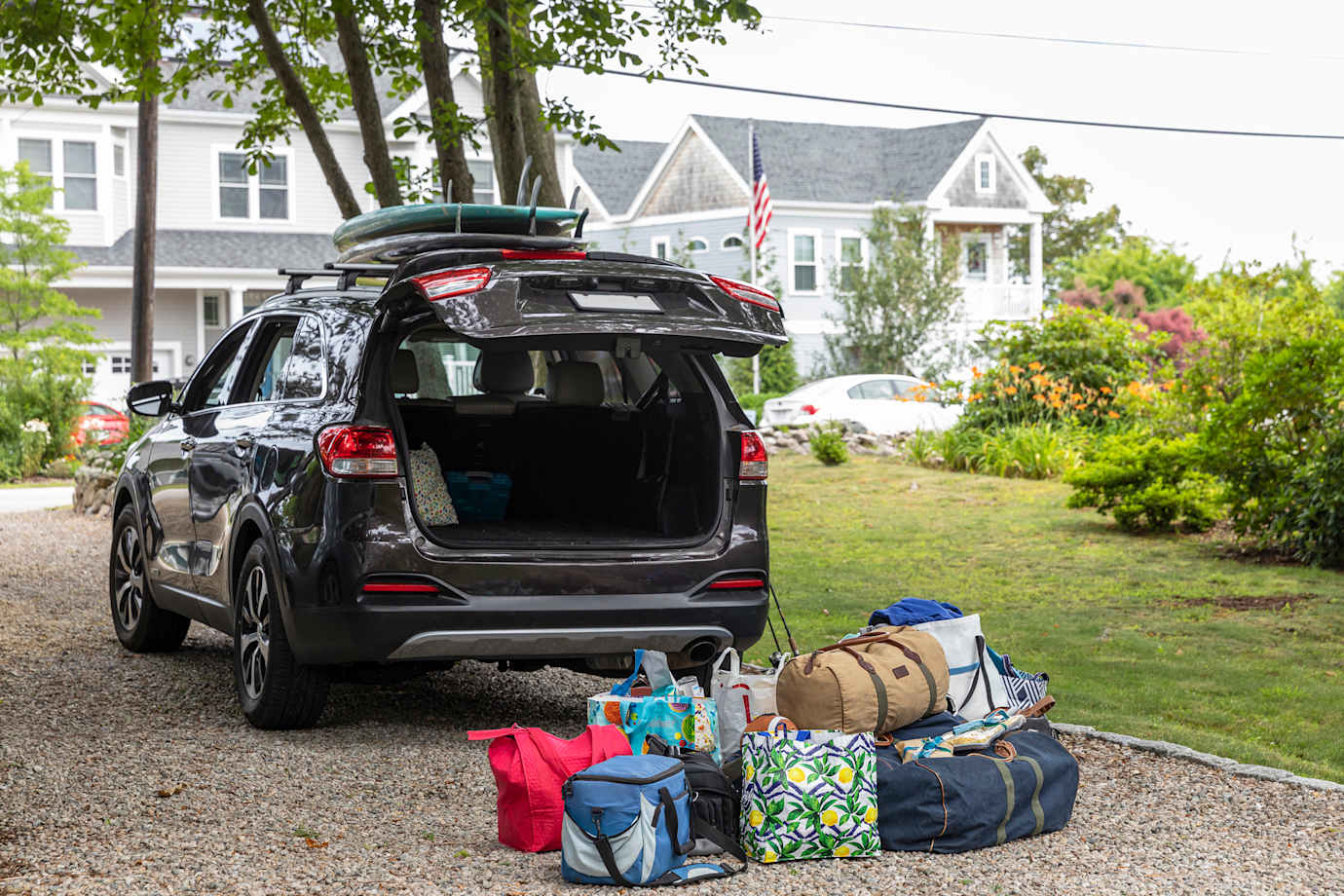 Bags are piled up behind an SUV to be loaded into the car before a road trip.