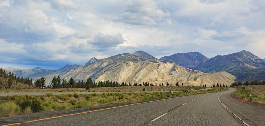 The pavement of Highway 395 in Northern California stretches towards the mountains in the distance.