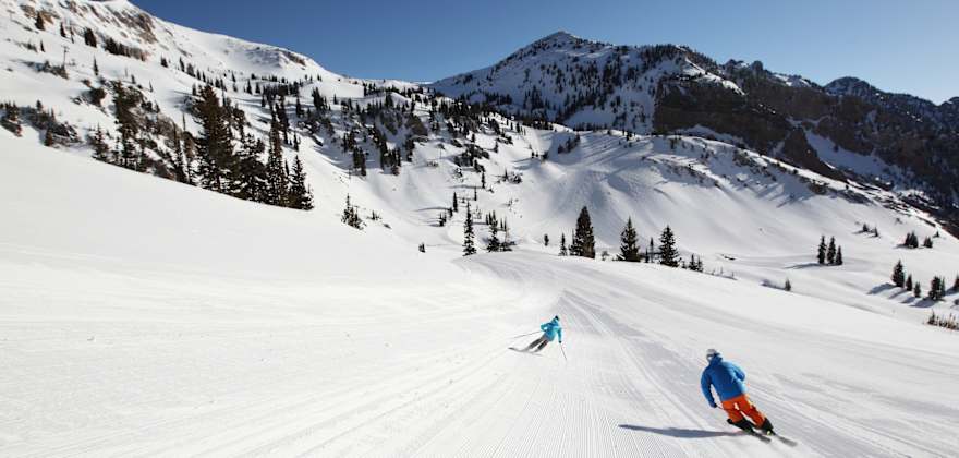 Man and woman skiing a groomed run at Snowbird in Salt Lake City