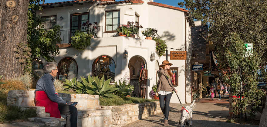 A woman walks her dog in Carmel-by-the-Sea, California