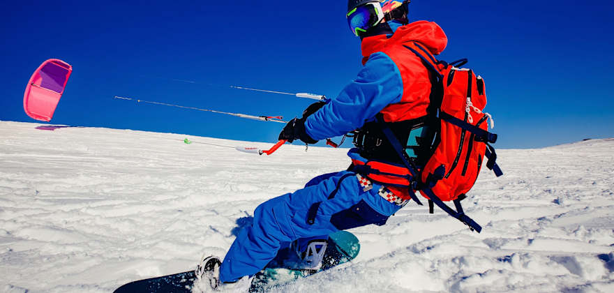 Snow kiter harnesses free wind energy on bright, cloudless day.