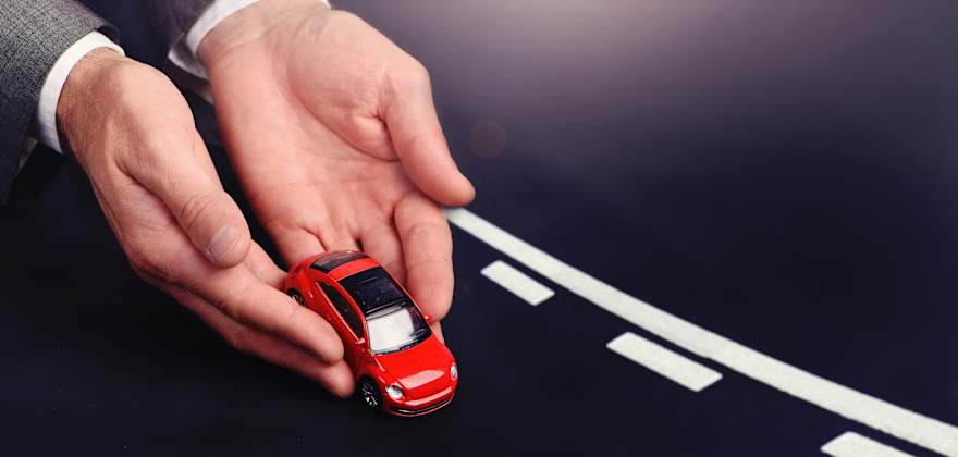 Two hands placing a red toy car on a road